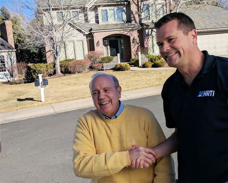 a man holding a hand of a man in front of a house